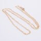 Gold Filled Tiny Hearts Chain Necklace laid on plain white background, looped into an N shape, at a slight angle