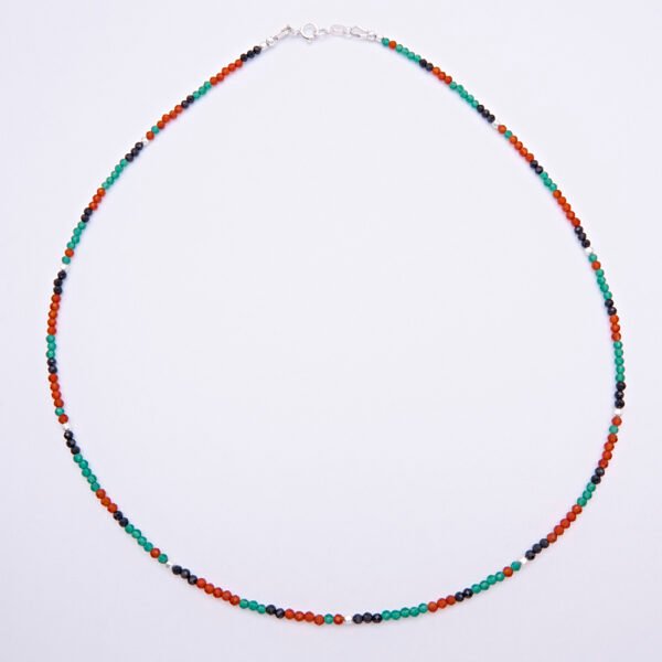 Green Onyx, Carnelian and dark blue Sapphire gemstone necklace with silver clasp shown from above on a plain white background