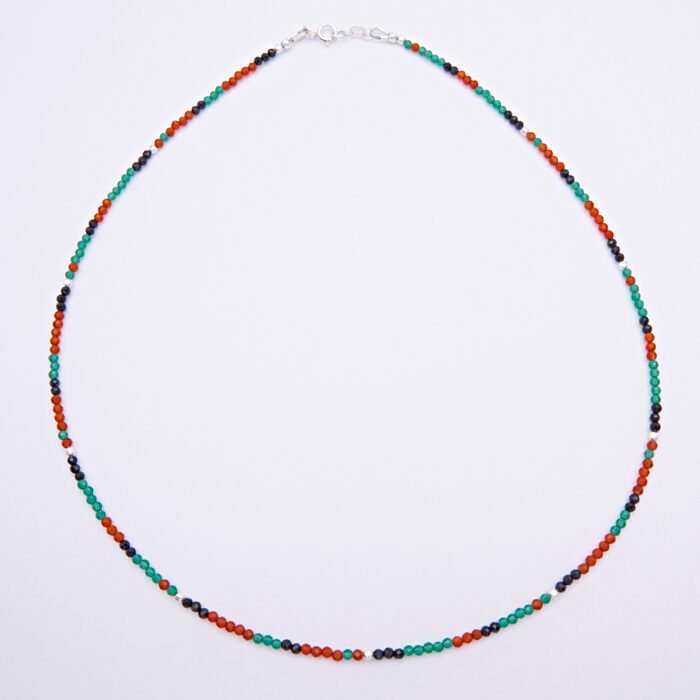 Green Onyx, Carnelian and dark blue Sapphire gemstone necklace with silver clasp shown from above on a plain white background