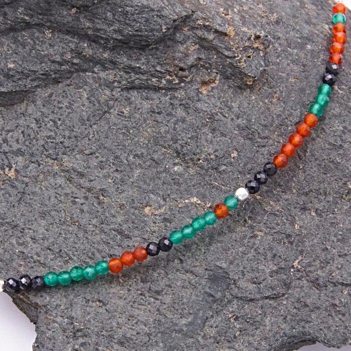 Green Onyx, Carnelian and dark blue Sapphire gemstone necklace with silver clasp, image shows a beaded section close-up on a dark grey stone
