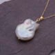 Baroque pear-shaped Freshwater Pearl Necklace, image shows close-up of pearl and part of chain on dark grey stone