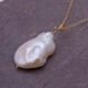 Baroque pear-shaped Freshwater Pearl Necklace, image is close-up of pearl and a little of the chain, shown on dark grey stone