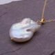 Baroque pear-shaped Freshwater Pearl Necklace, image shows close-up from the side of the pearl and part of the chain, on a dark grey stone