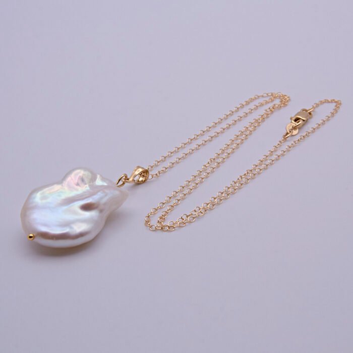 Baroque pear-shaped Freshwater Pearl Necklace shown on flat white surface with pearl at the bottom of the image and chain looped in a loose N shape