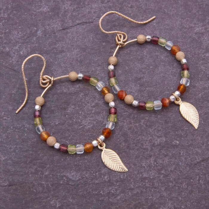 Gold Filled Gemstone Hoop Earrings with Gold Leaf Charm, shown from above on dark slate background