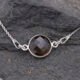 Smoky Quartz or Crystal Quartz round bezel set faceted gemstone Sterling Silver necklace Smoky Quartz or Crystal Quartz round bezel set faceted gemstone Sterling Silver necklace, image shows close-up of Smoky Quartz gemstone on dark grey stone