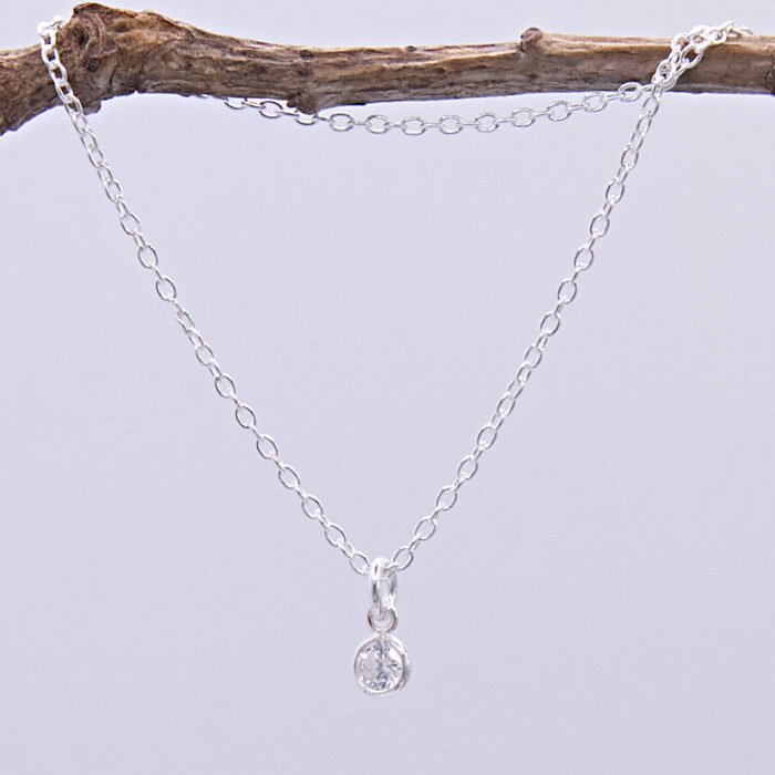 Cubic Zirconia Bezel-set stone on Sterling Silver Chain, image shows necklace hanging from twig