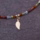Mixed Metals Gemstone Necklace with Gold Leaf Charm, image shows close-up of front of leaf charm and part of gemstone strand, on dark slate background