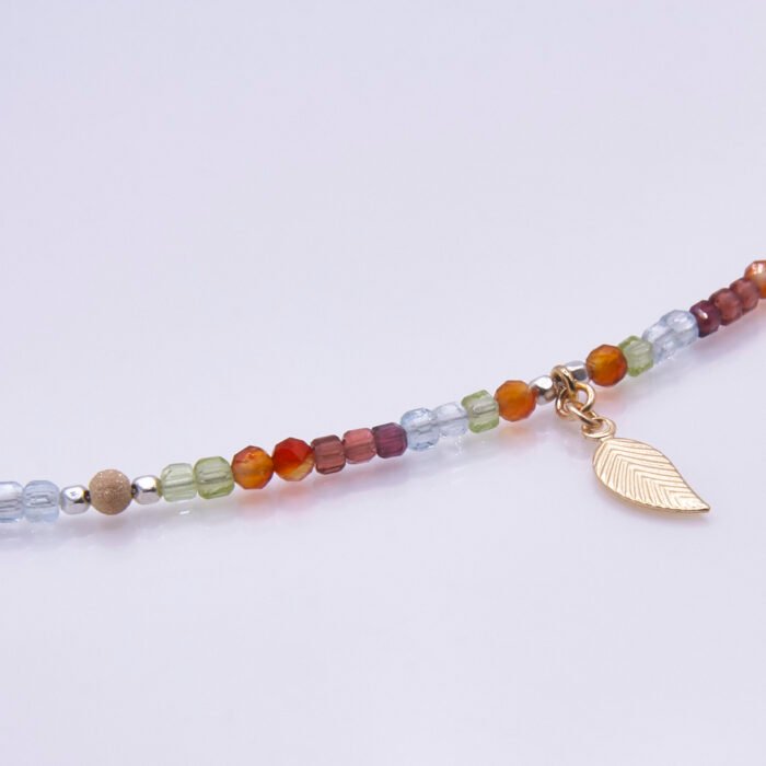 Mixed Metals Gemstone Necklace with Gold Leaf Charm, image shows close-up of leaf and part of gemstone strand, with leaf on the right, on plain white background