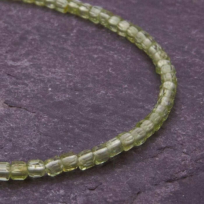 Peridot and Sterling Silver Bracelet, image shows close-up of part of gemstone strand on dark slate background