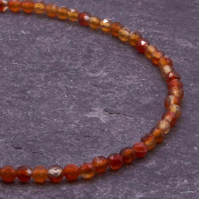 Carnelian and Sterling Silver Bracelet, image shows close-up of part of gemstone strand on dark slate background