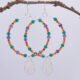 Mixed Gemstone Large Hoop Earrings with Wildflower Charm, shown hanging from twig with plain white background